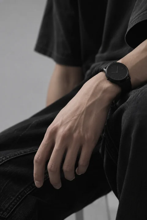 KAI’s wrist and black watch, with the full hand and fingertips visible
