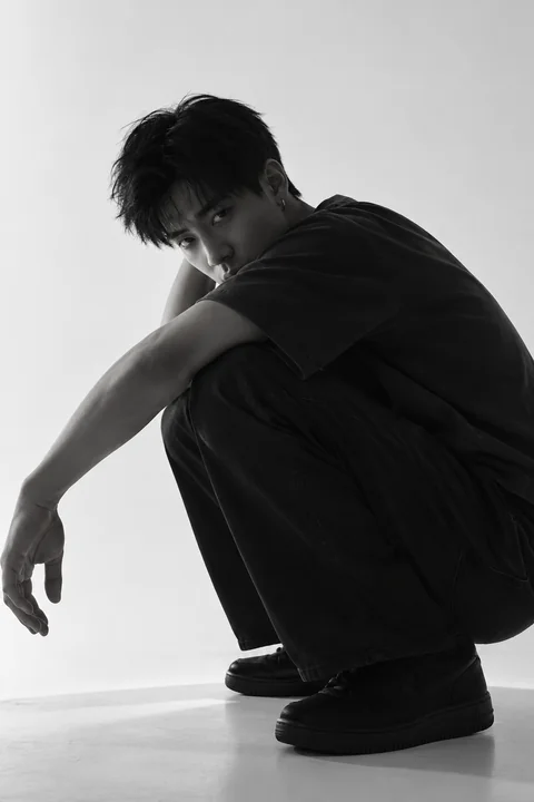 Black-and-white portrait of KAI crouching, preserving the complete pose and shoes